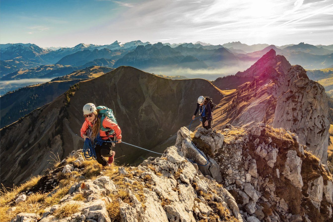 Two climbers roped together, cresting a mountain ridge